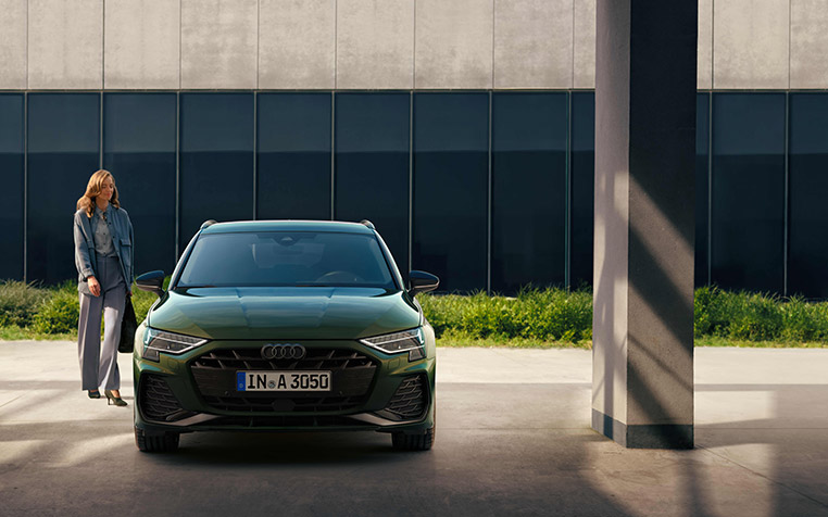 Frau steht neben einem Audi A3 Sportback. 