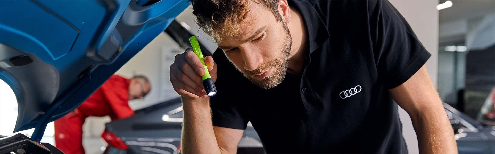 Mann untersucht mit Taschenlampe Motorraum