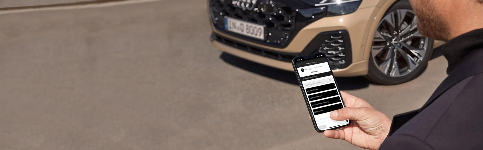 Sicht auf Handy auf der Onlineterminvereinbarung Seite von Audi Stuttgart mit Fahrzeug im Hintergrund.
